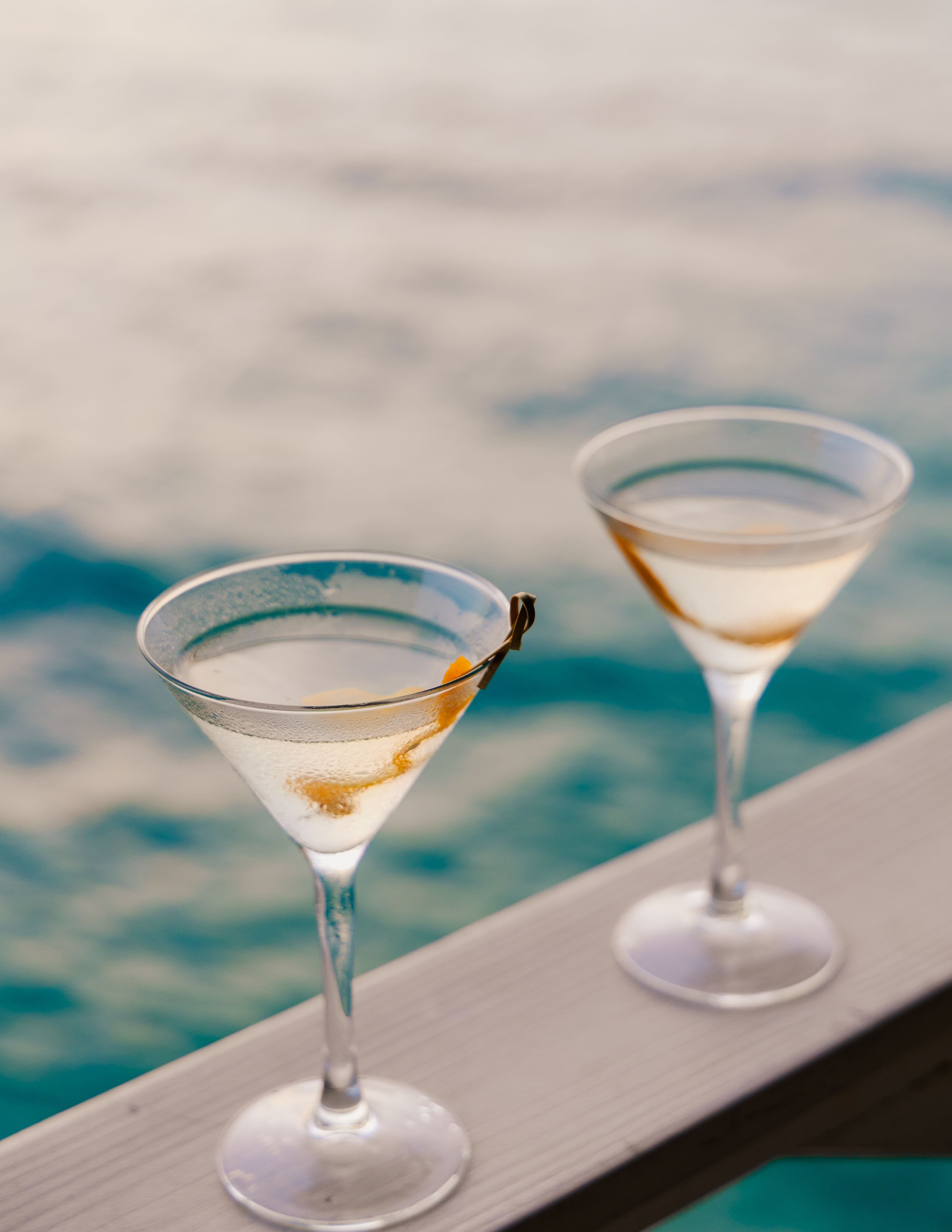 two glasses of liquid on a railing