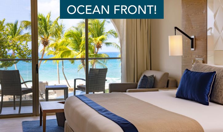 a room with a bed and chairs and a table and chairs and a beach view