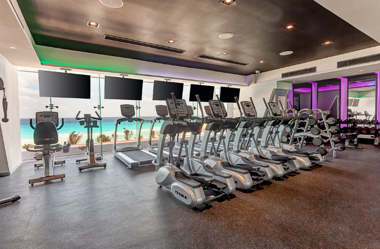 a room with exercise machines and screens