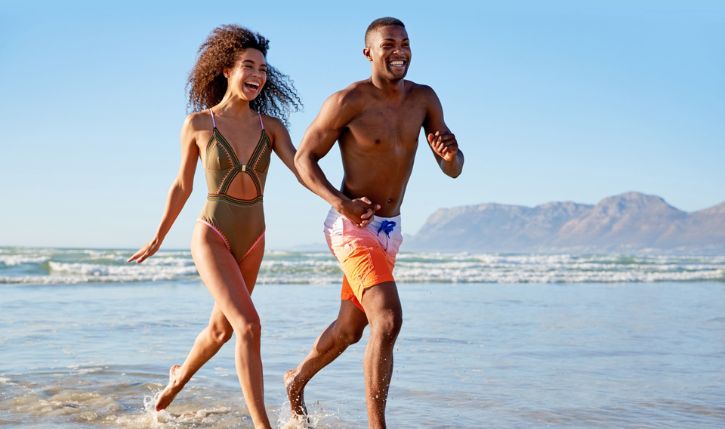 a man and woman running on a beach
