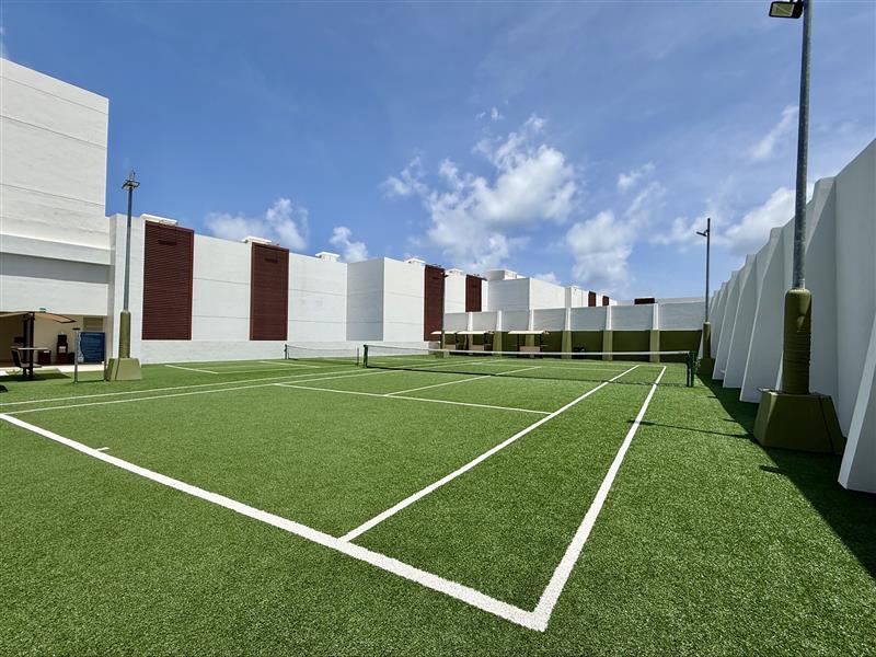 a tennis court with white walls and a building