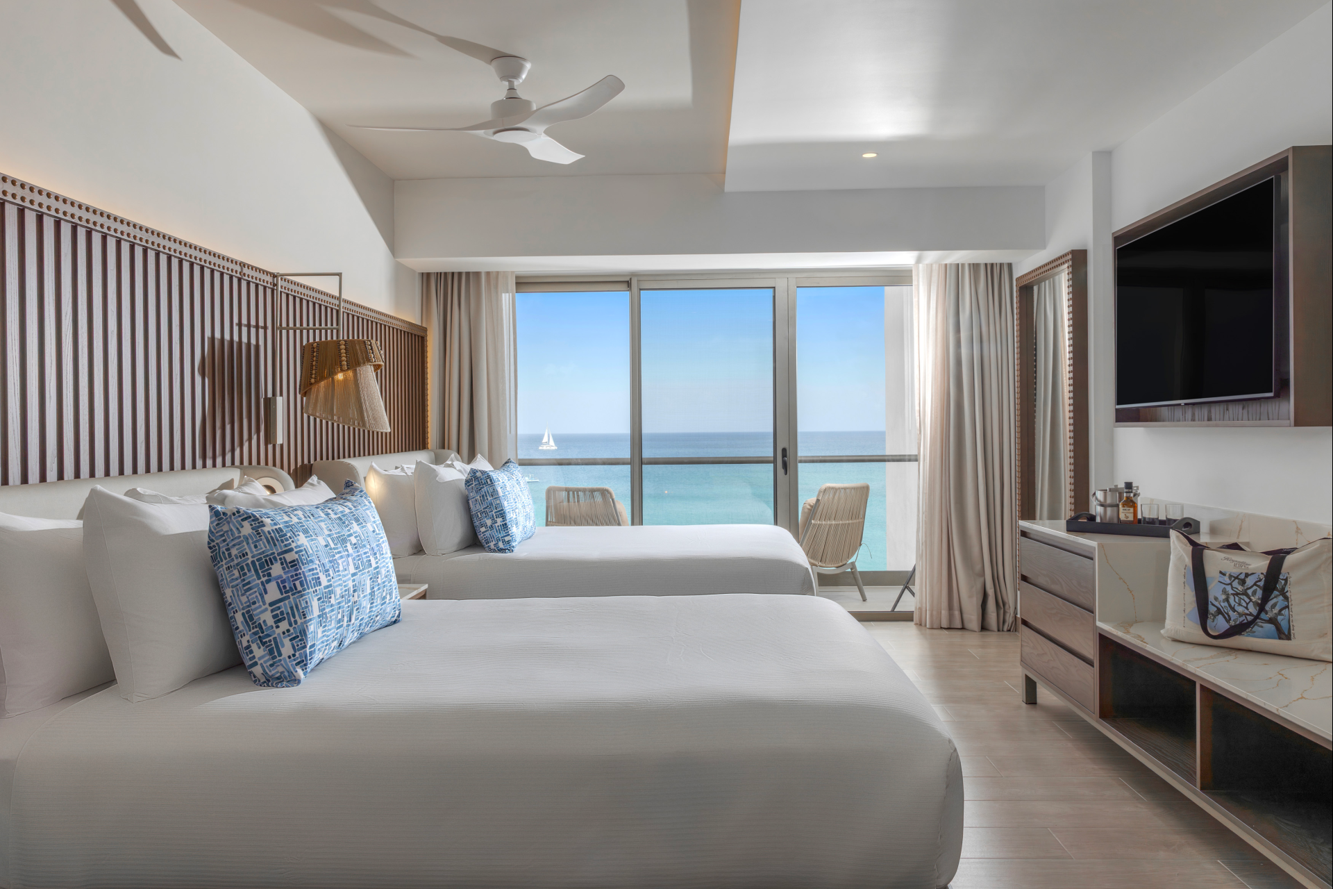 a room with two beds and a dresser with a fan and a window