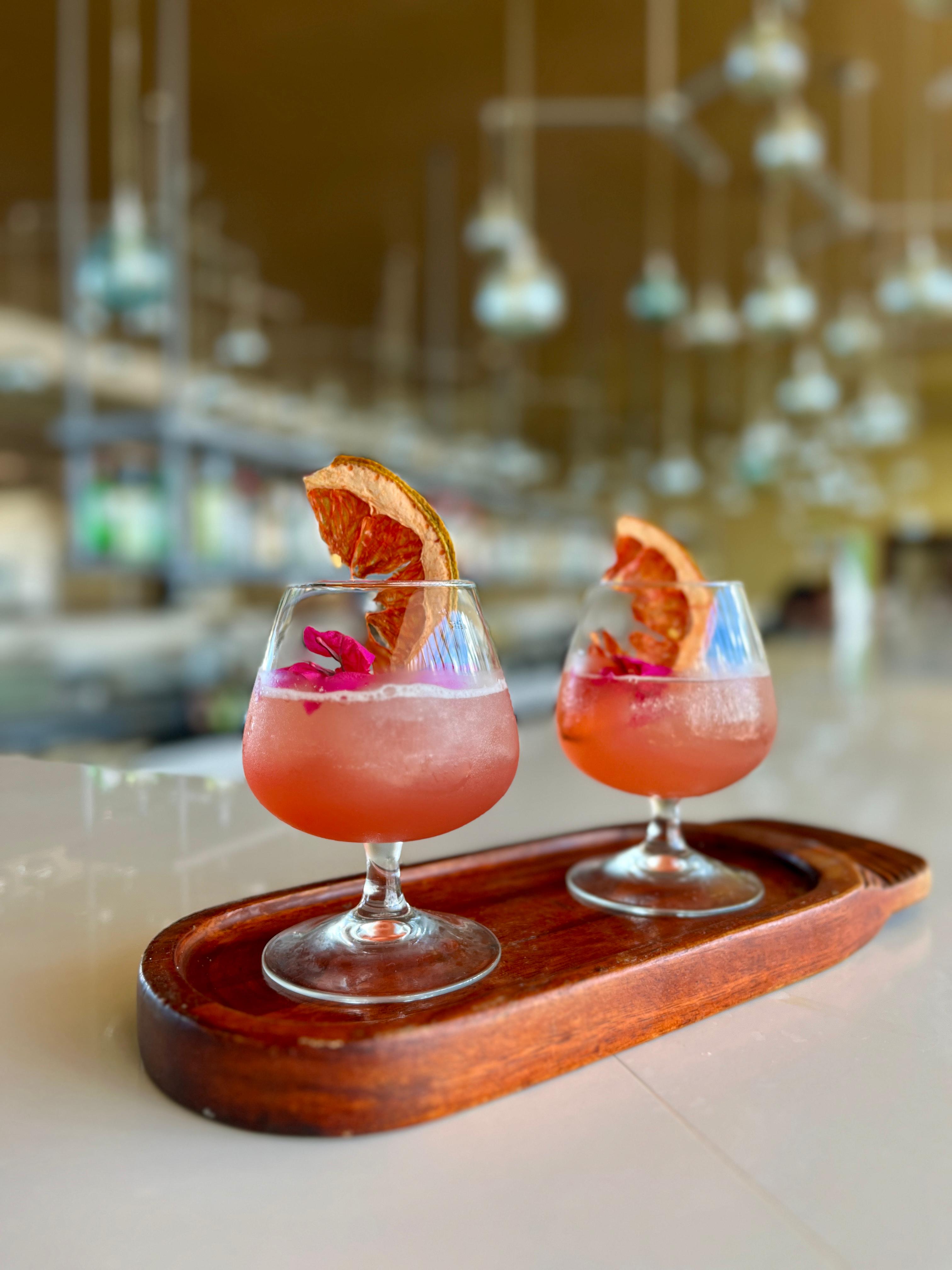 two glasses of pink drinks on a wooden tray