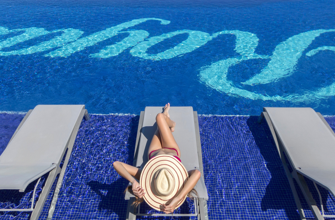 a woman lying on a lounge chair by a pool