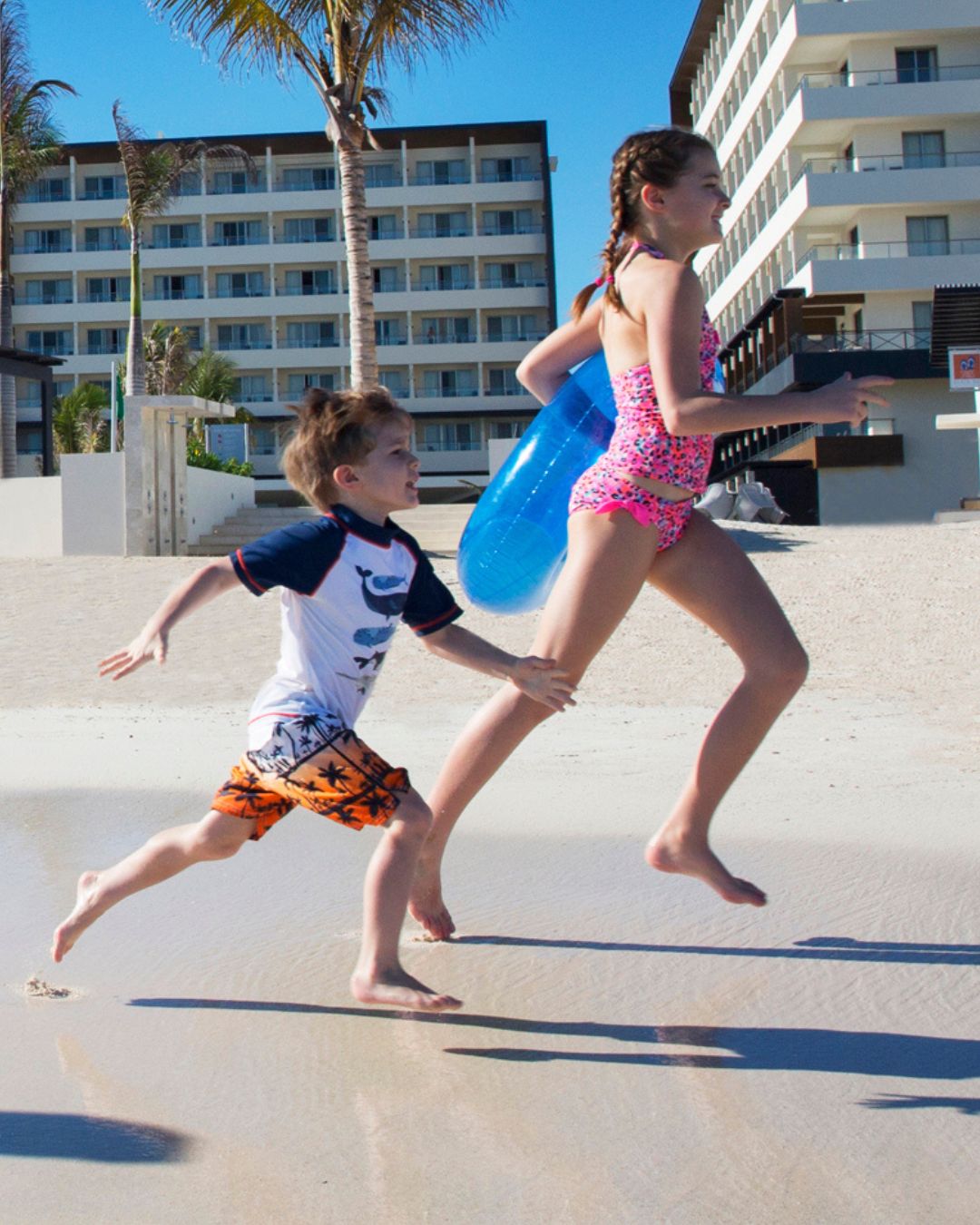 a boy and girl running on a beach