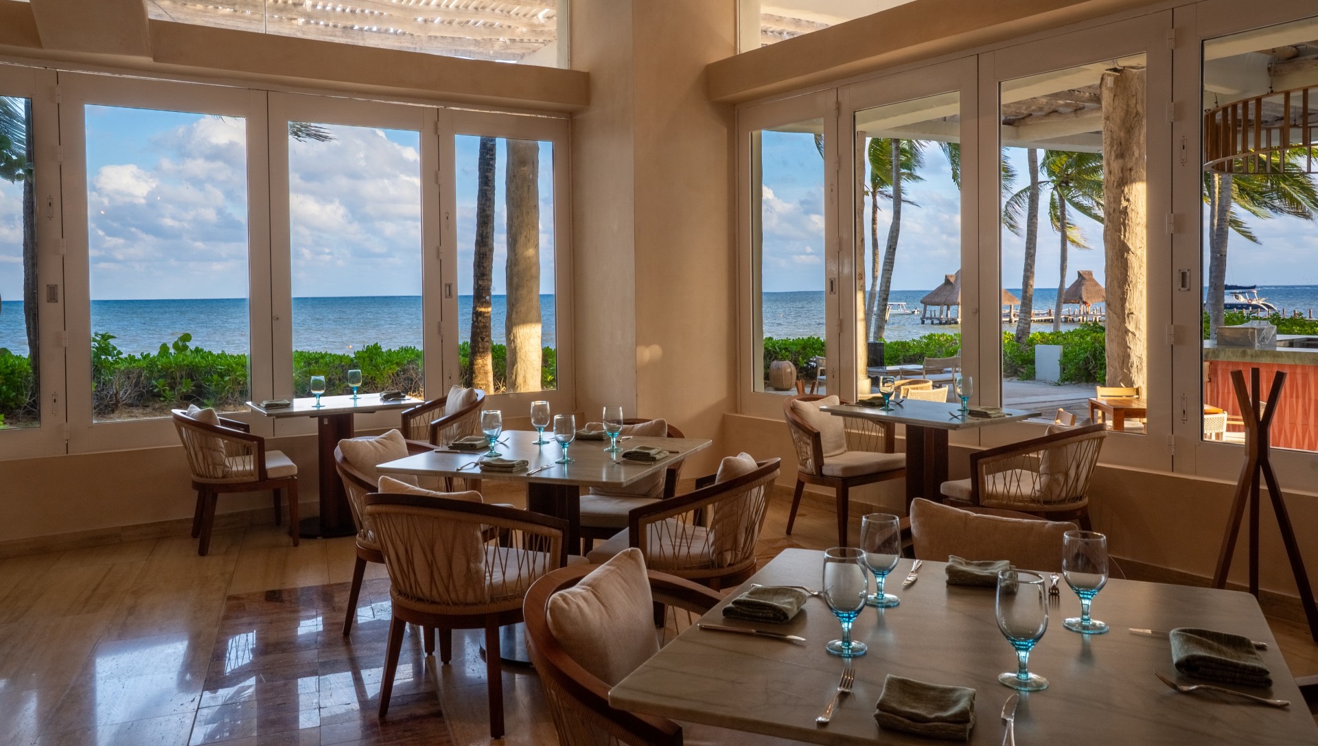 a room with tables and chairs and a view of the ocean