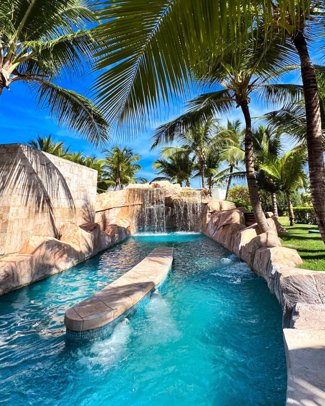 a pool with a waterfall and palm trees
