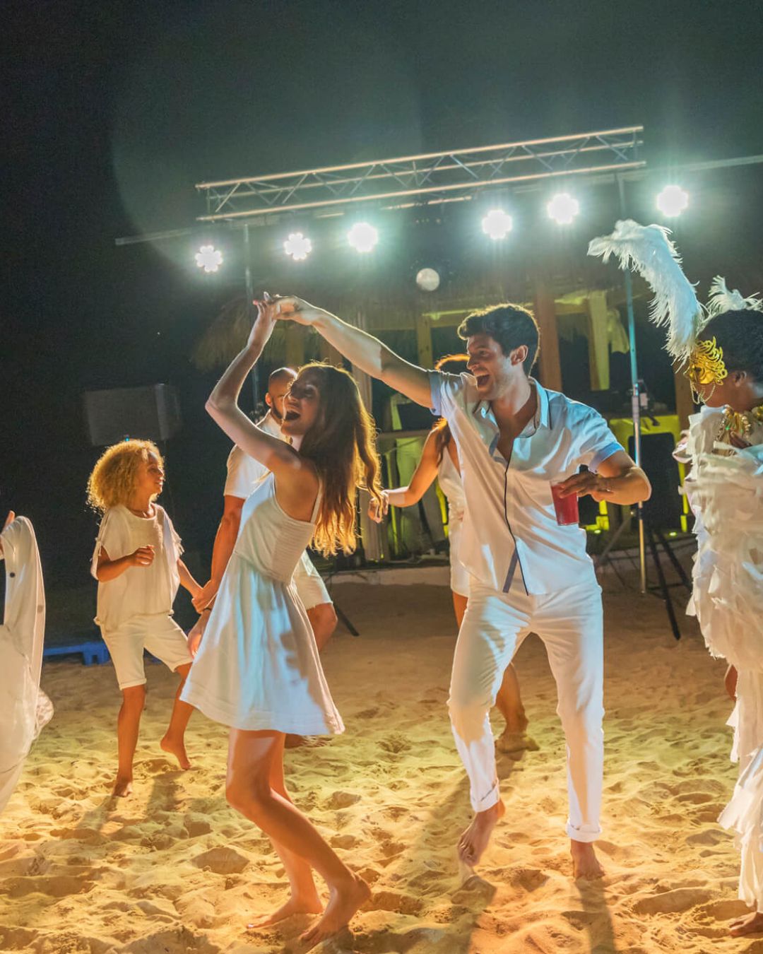 a group of people dancing on a beach