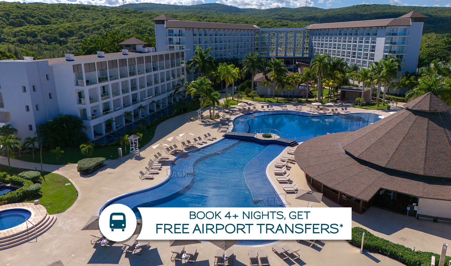 a swimming pool with lounge chairs and a large building with trees in the background