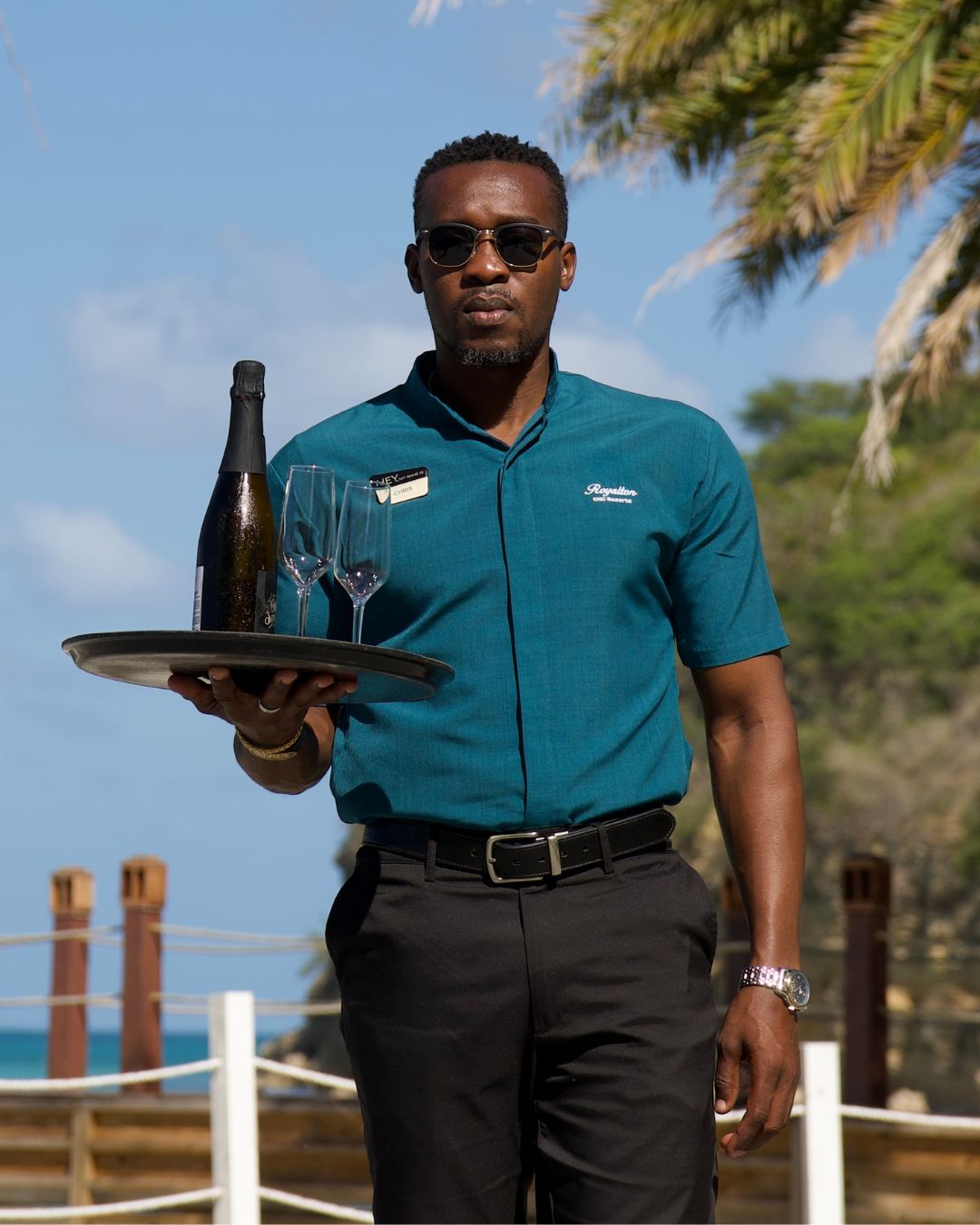 a man holding a tray with wine and glasses