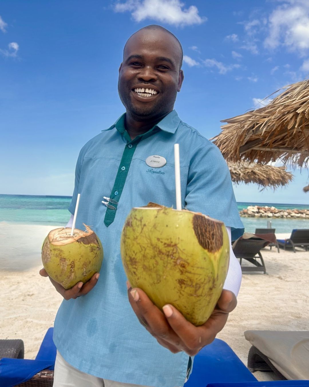 a man holding two coconuts on a beach