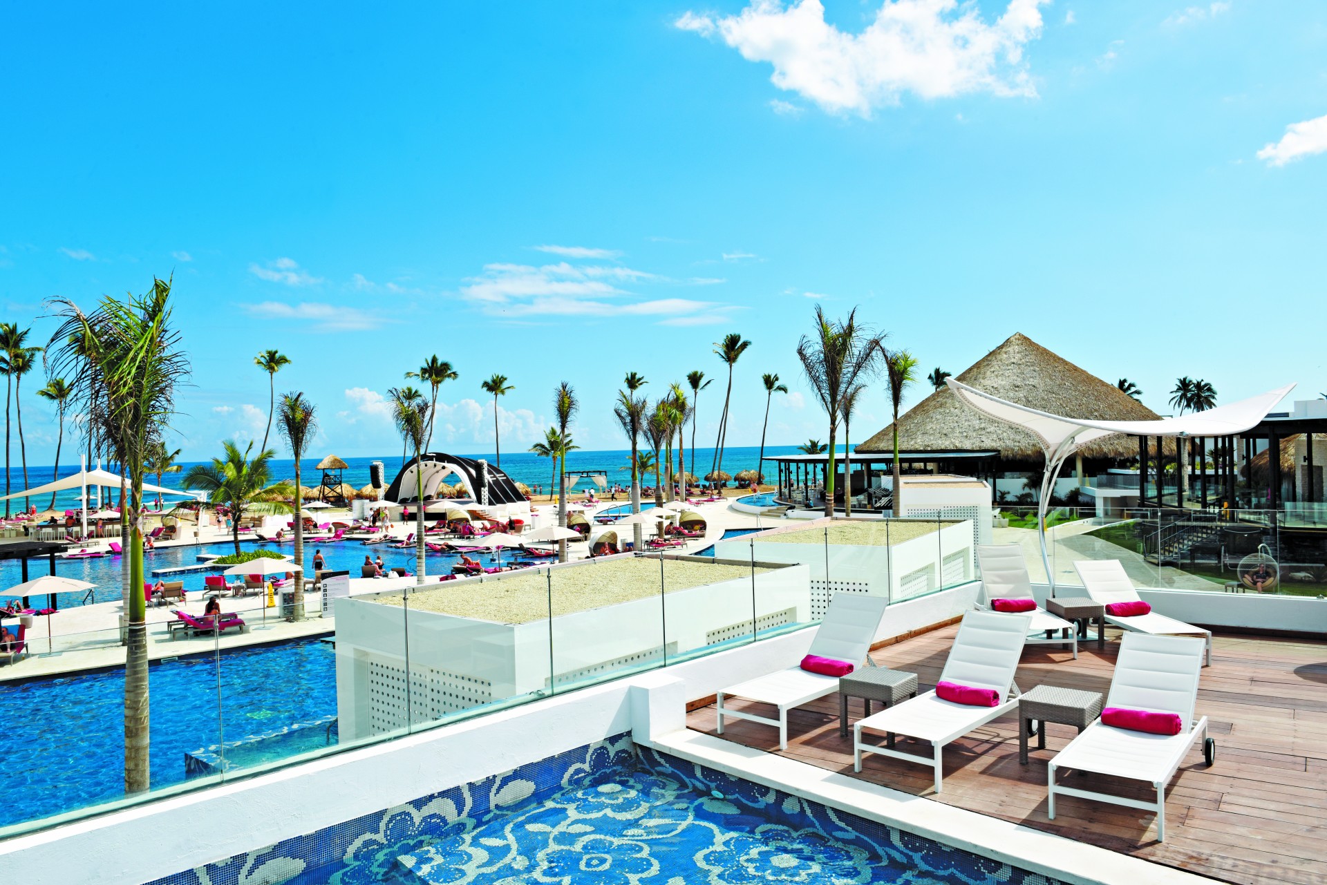 a pool with lounge chairs and a beach and palm trees