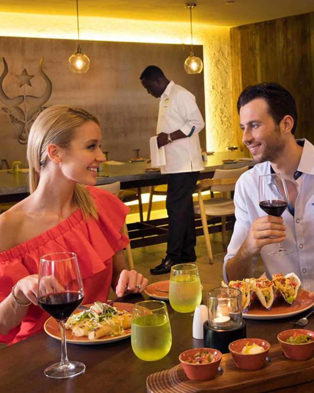 a man and woman sitting at a table with food and wine