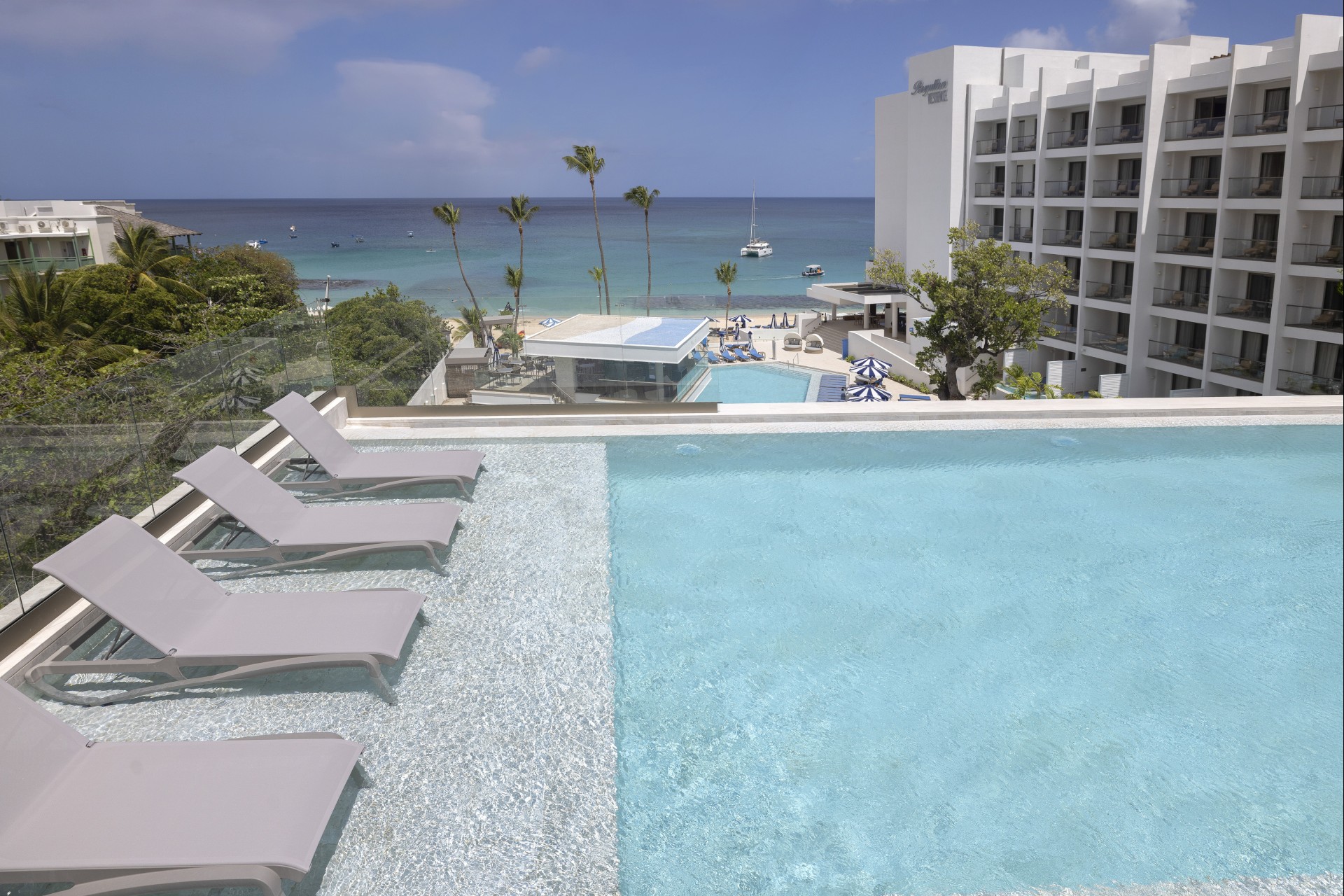 a pool with lounge chairs and a beach in the background