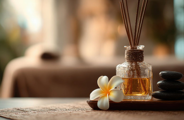 a glass bottle with sticks next to a flower