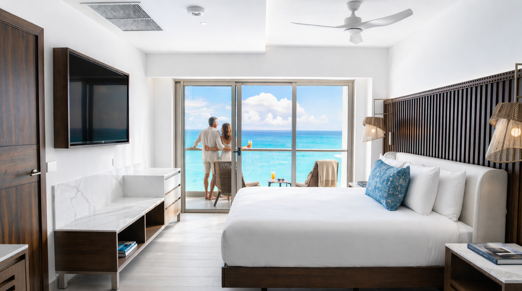 a couple standing in a hotel room looking out to the ocean