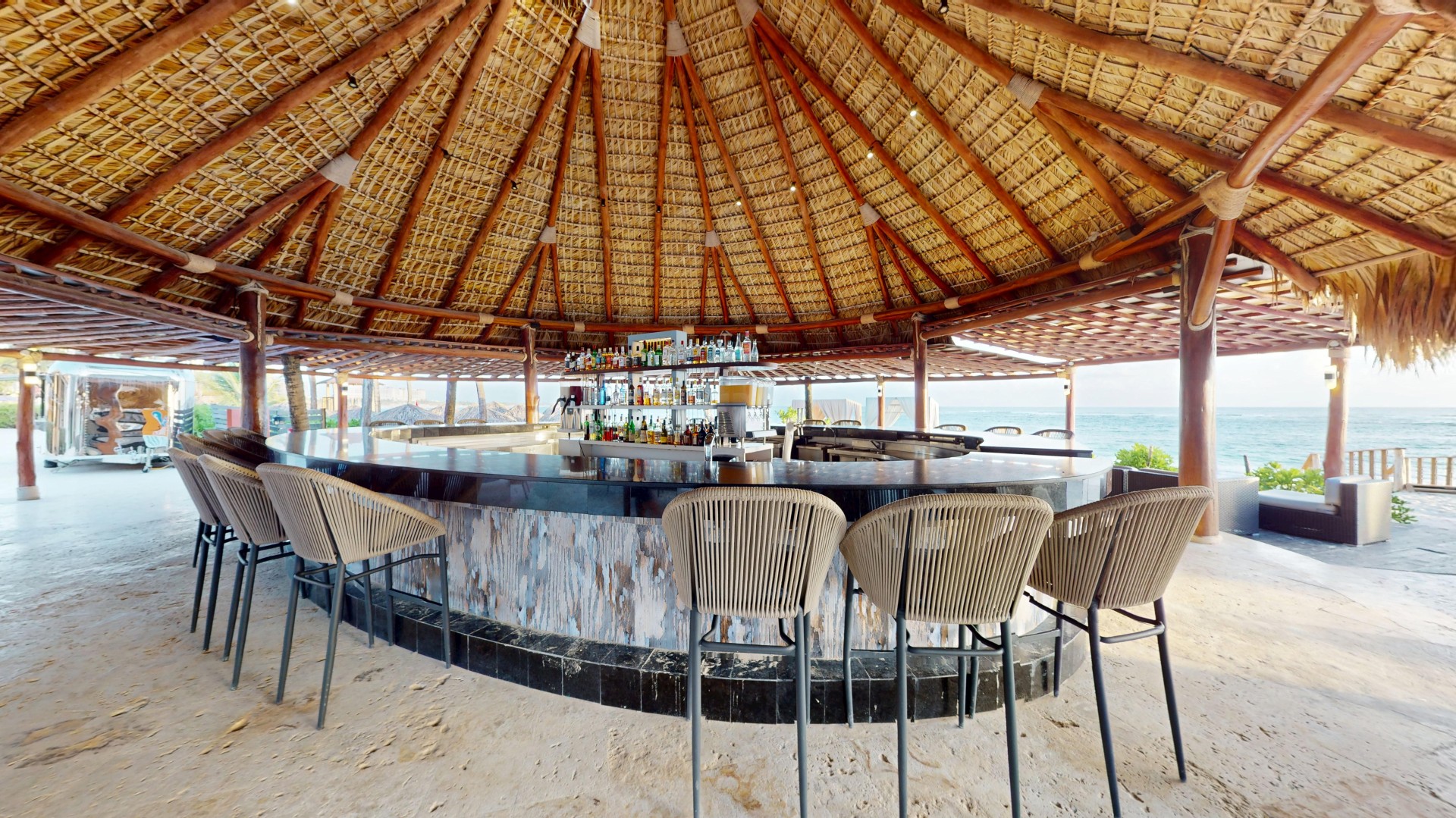 a bar with chairs and a thatched roof