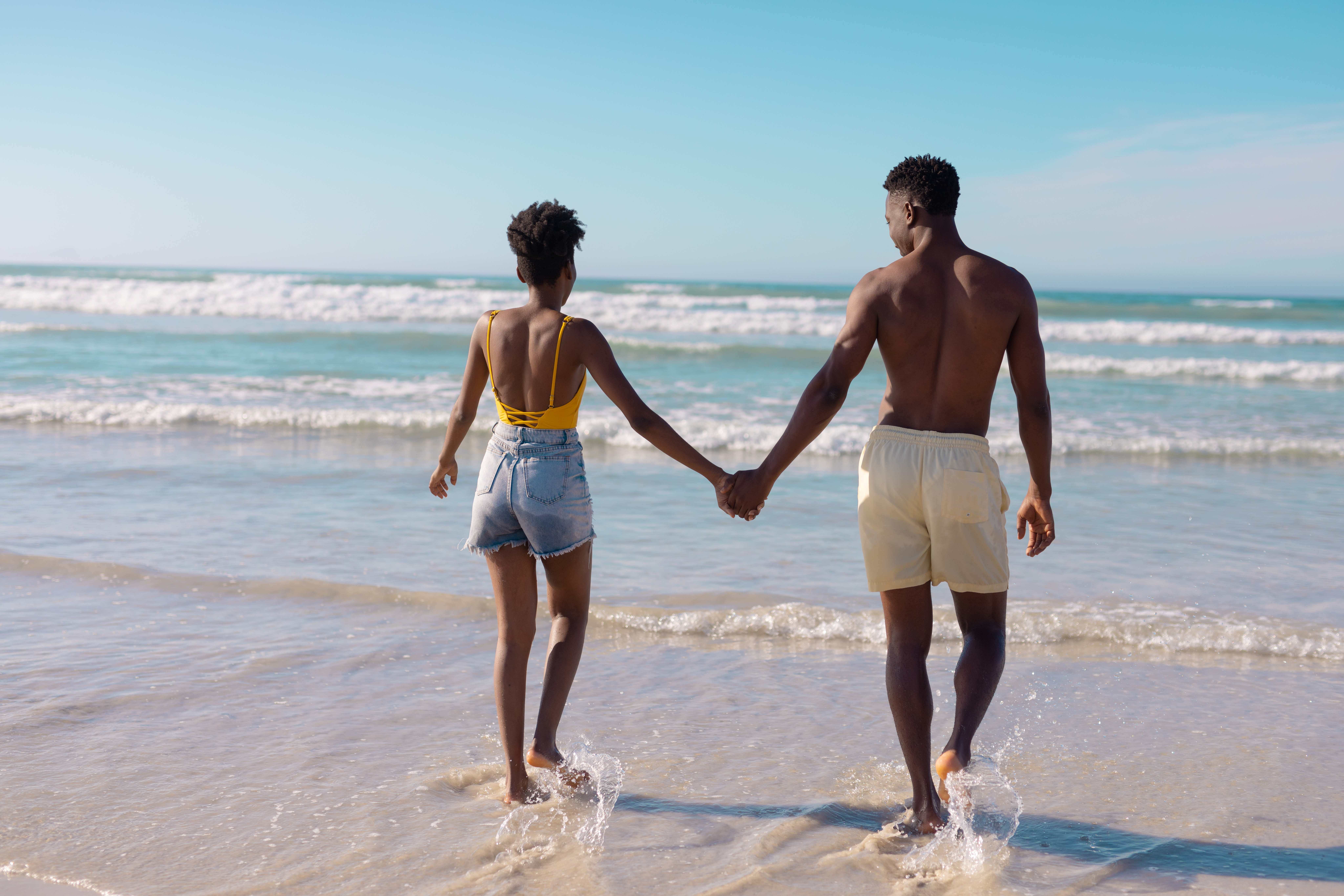 a man and woman holding hands on a beach