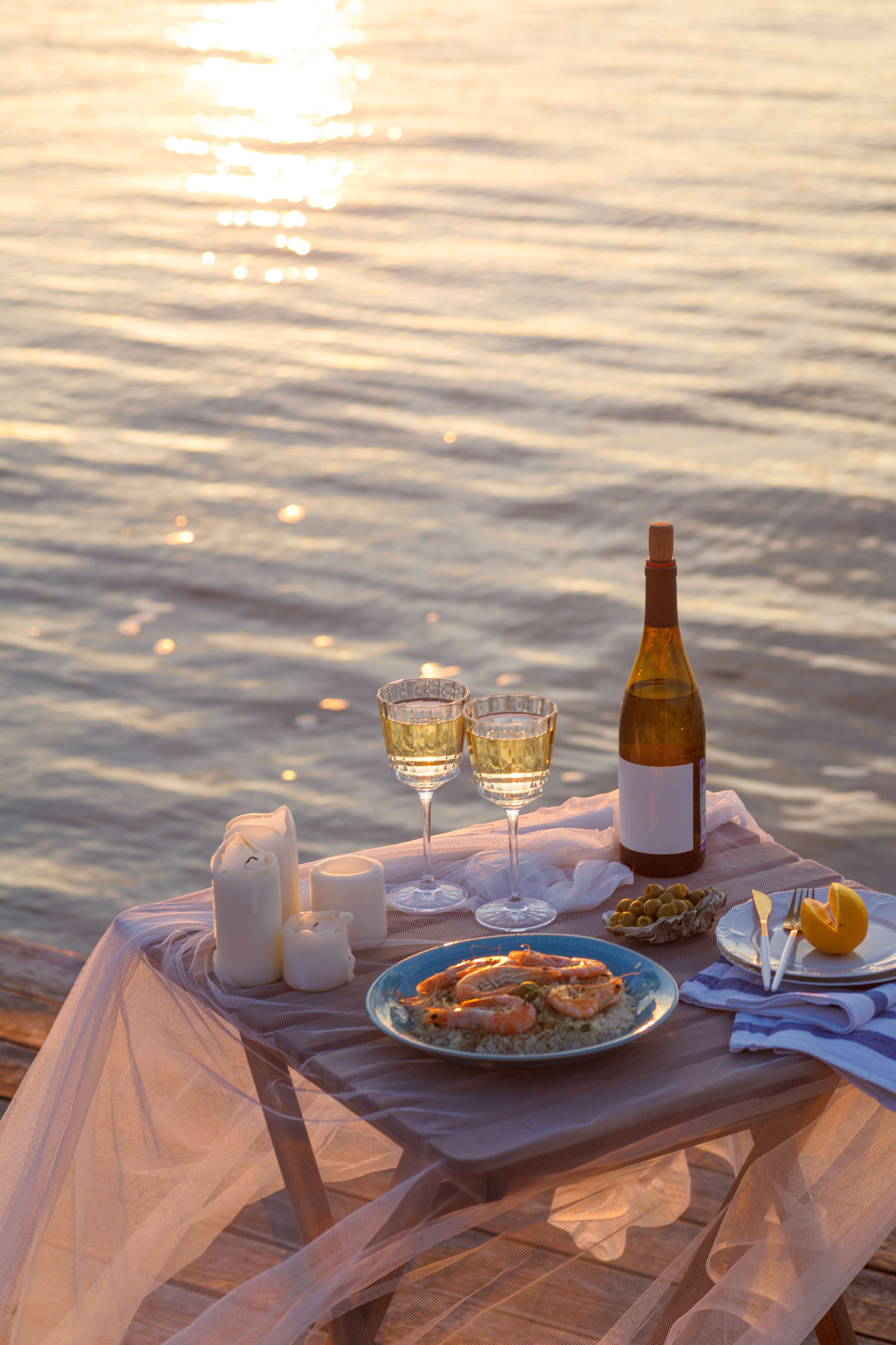 a table with food and wine on it by the water