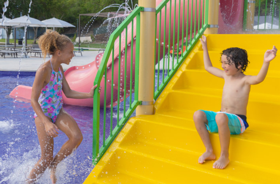 a boy and girl playing on a water slide
