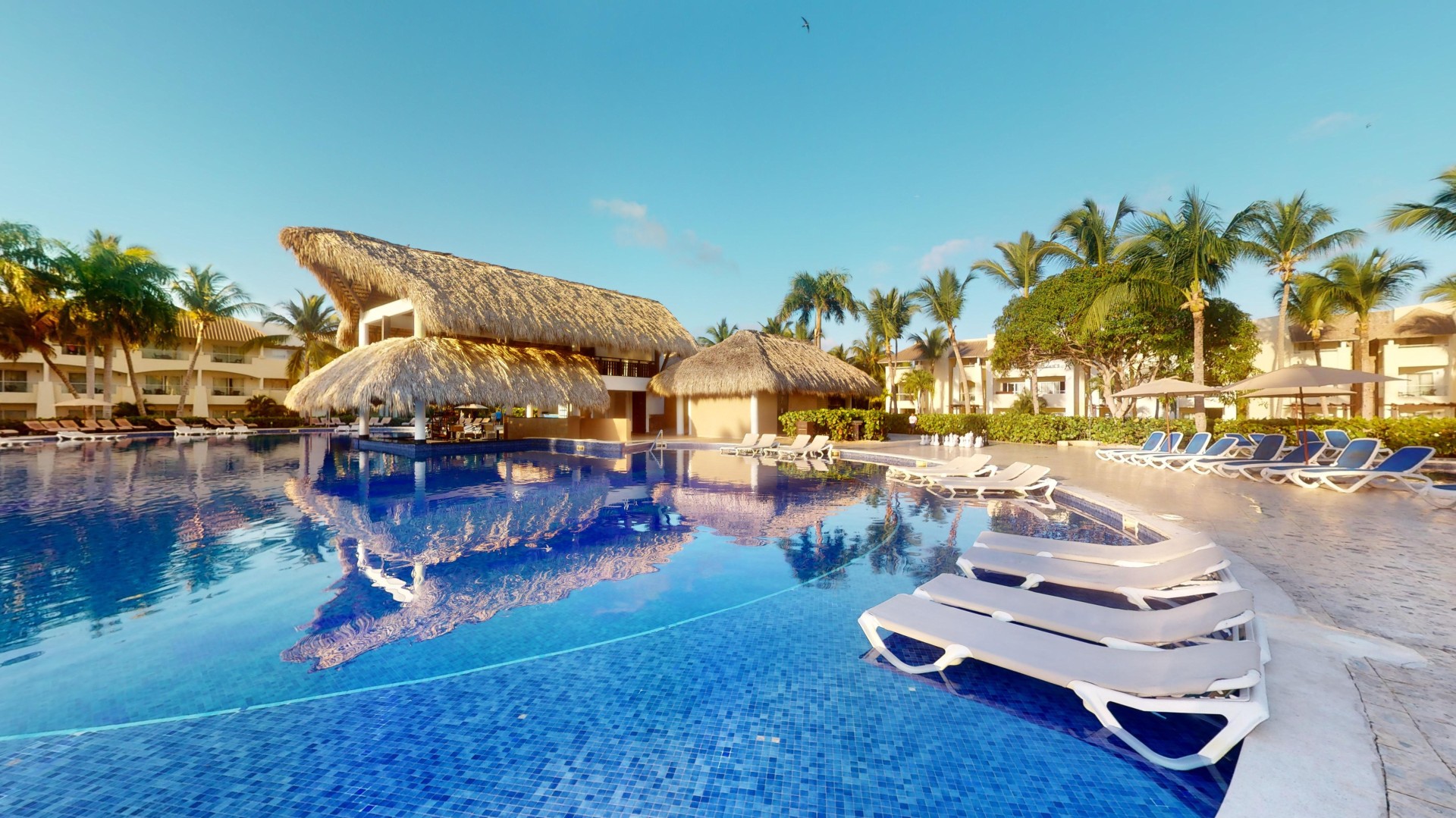 a pool with lounge chairs and a thatched roof