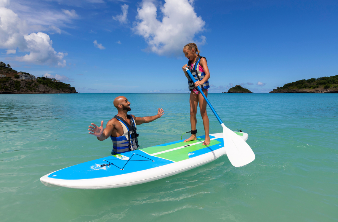 a man and a girl on a paddle board in the water