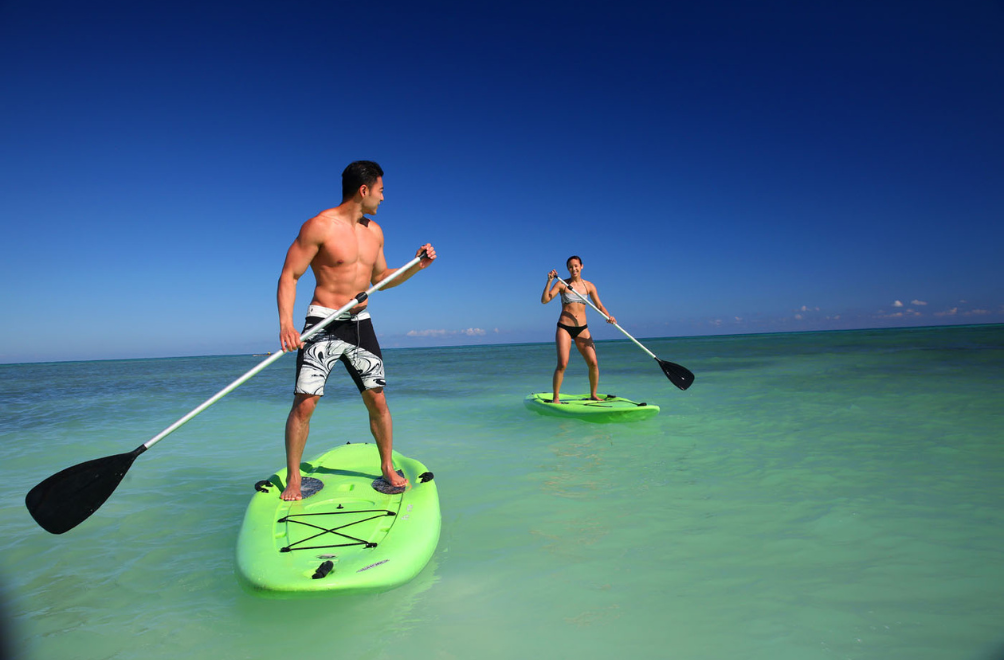 a man and woman on paddle boards in water