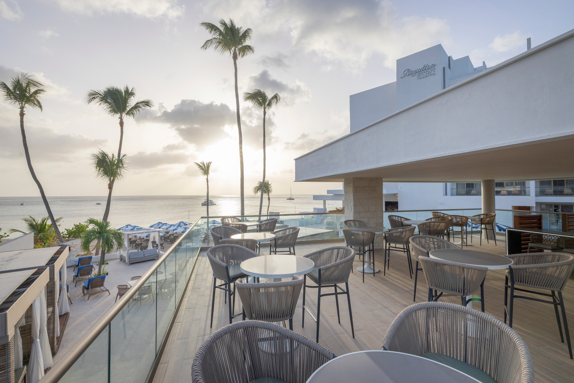 a patio with tables and chairs on a deck overlooking a body of water