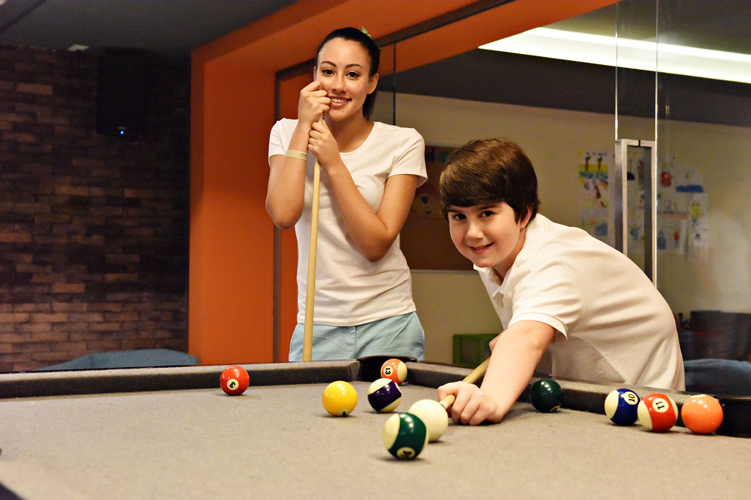 a boy and girl playing pool