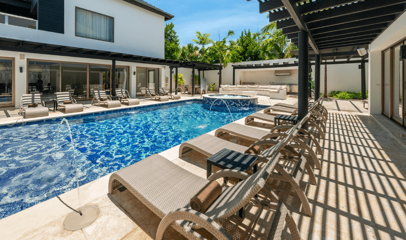 a pool with lounge chairs and a hot tub