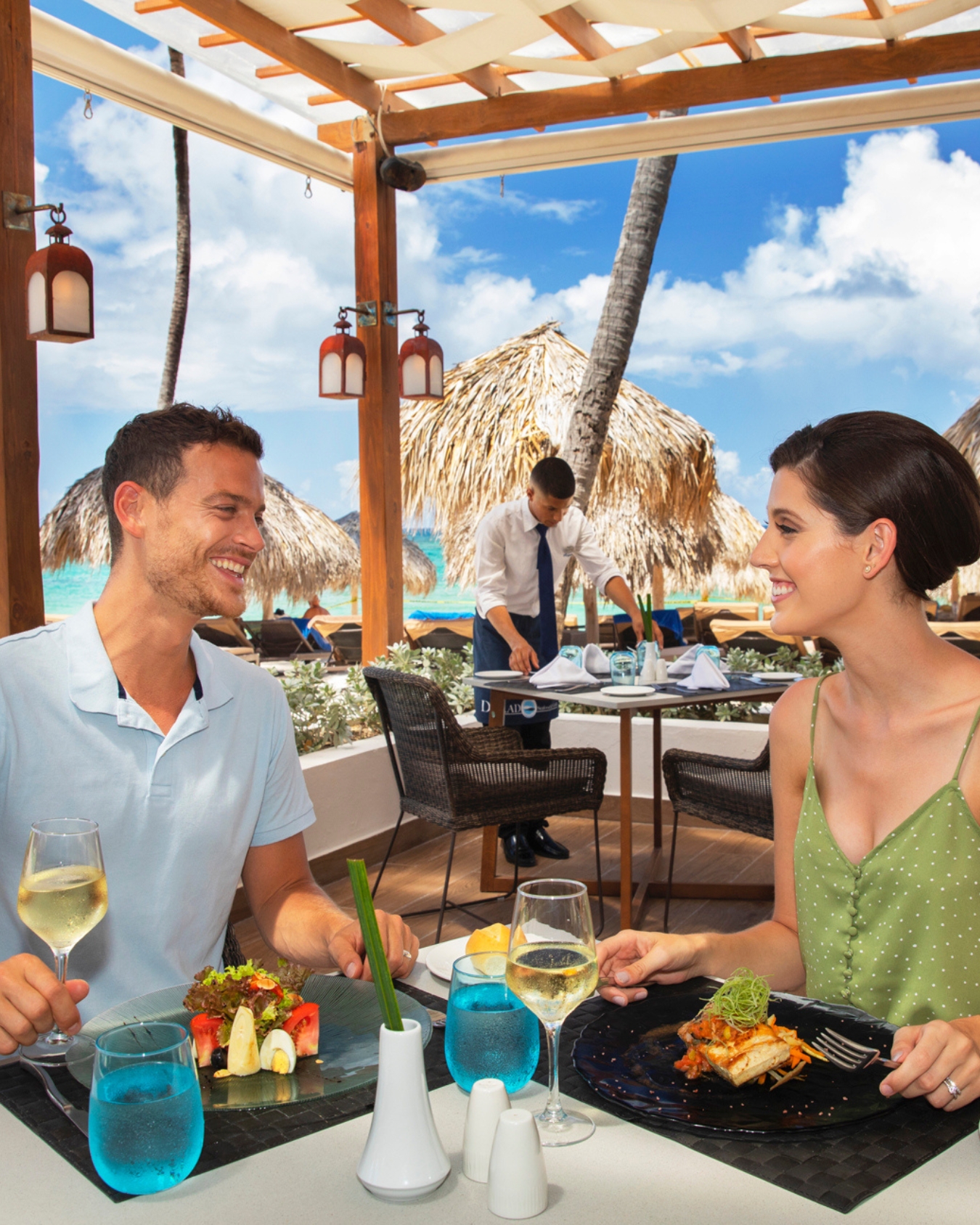 a man and woman sitting at a table with food and drinks