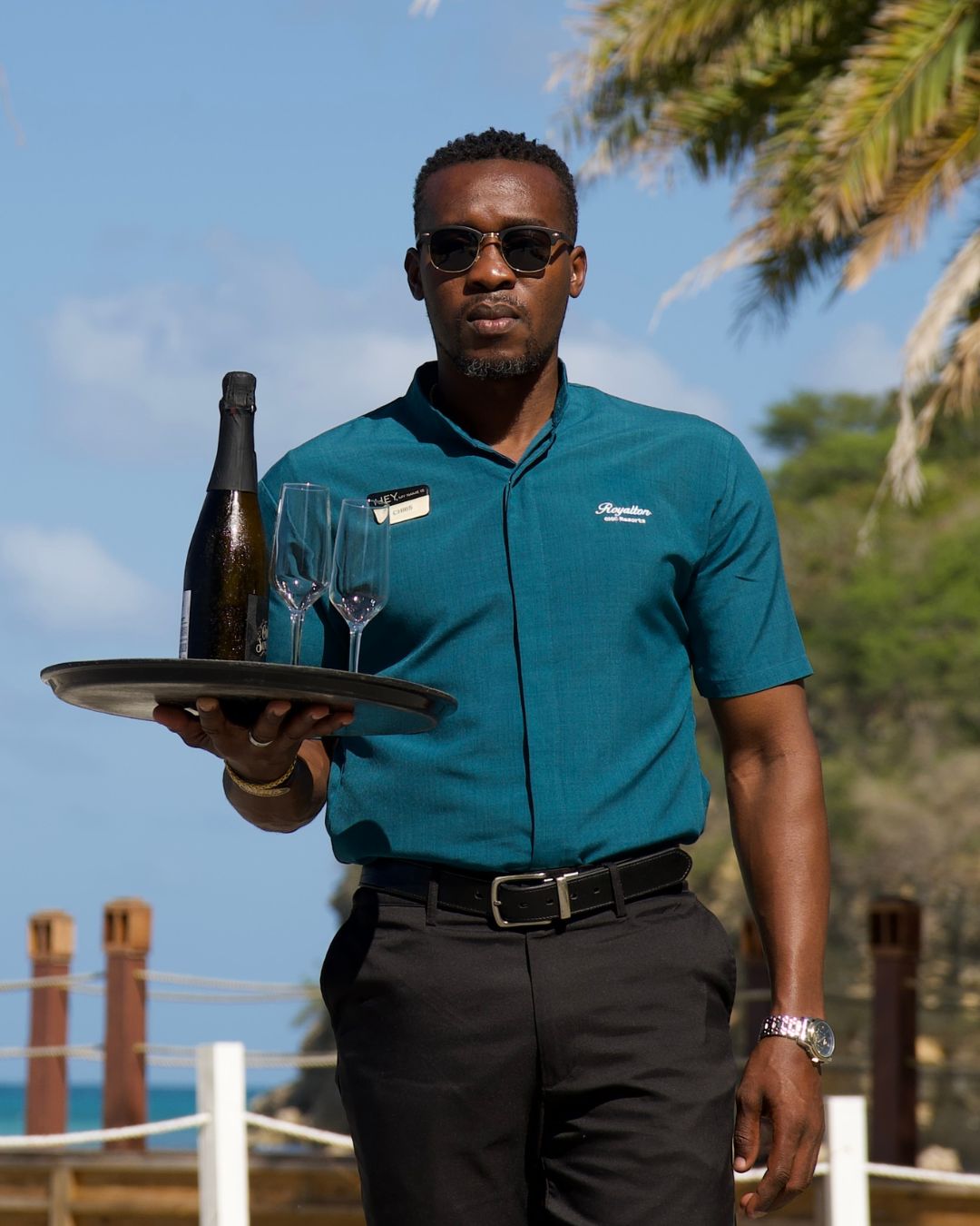 a man holding a tray with wine and glasses