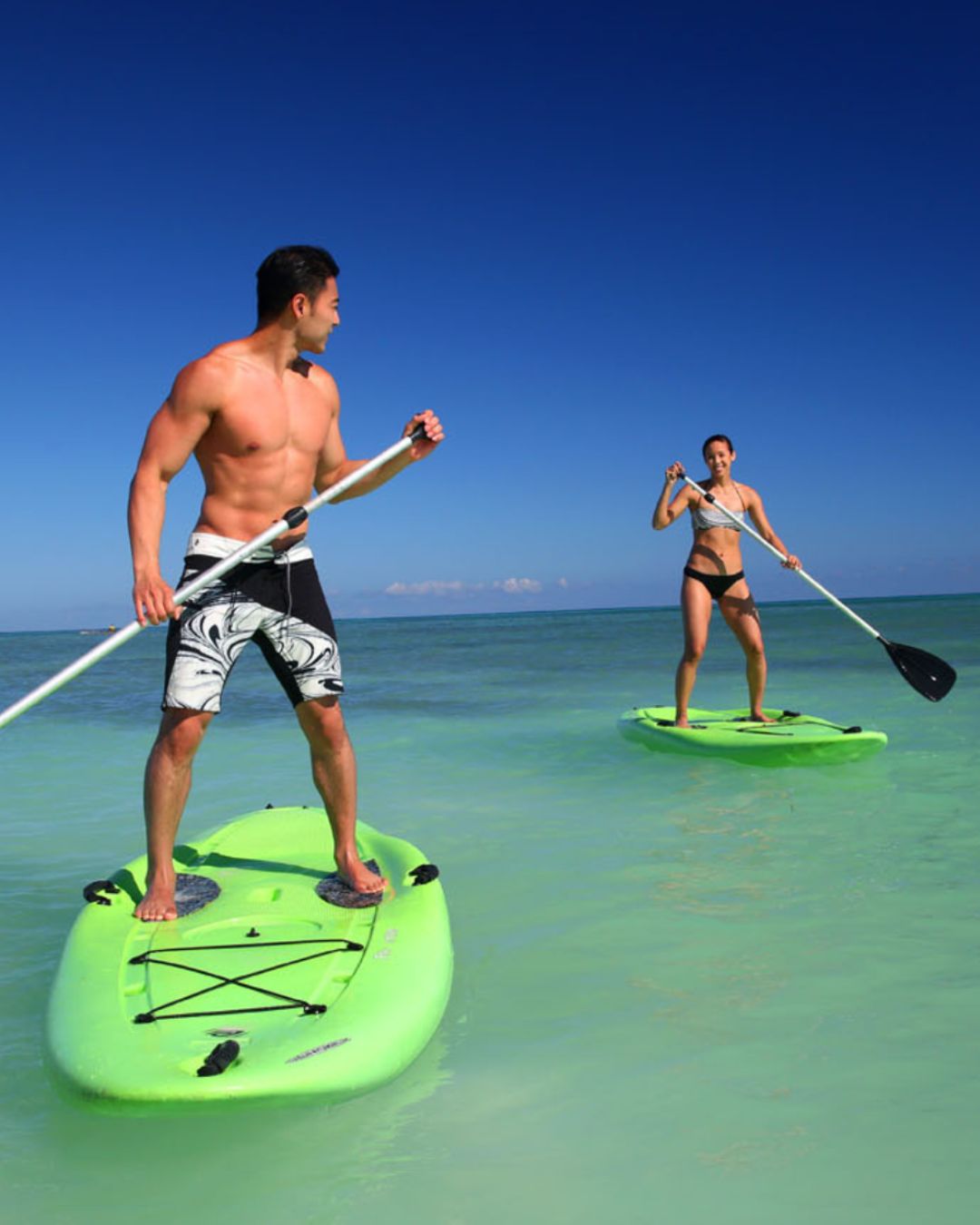 a man and woman on paddle boards in the water