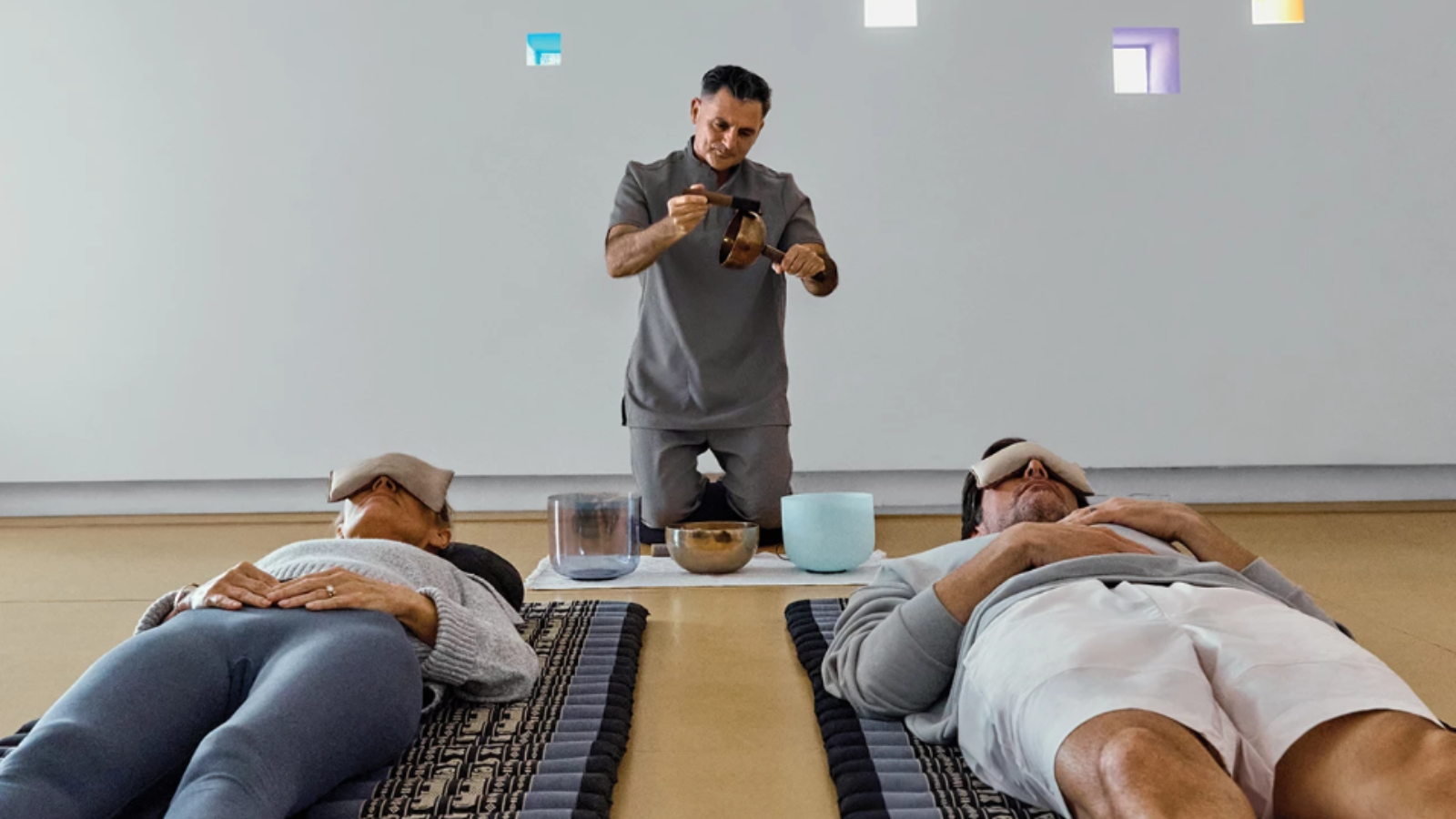 a man holding a wooden object above a group of people lying on mats