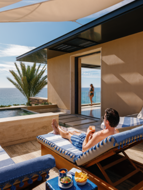 a man sitting on a lounge chair with a drink on the back
