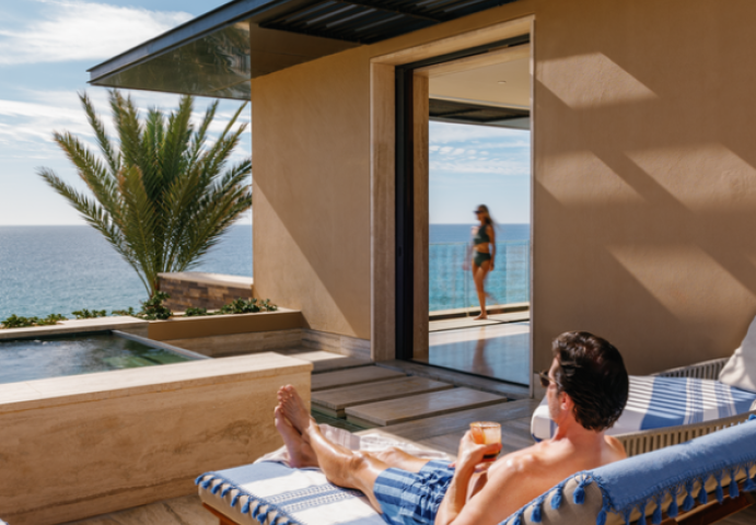 a man sitting on a lounge chair with a drink on the back