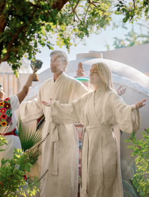 a group of people in white robes standing under a tree