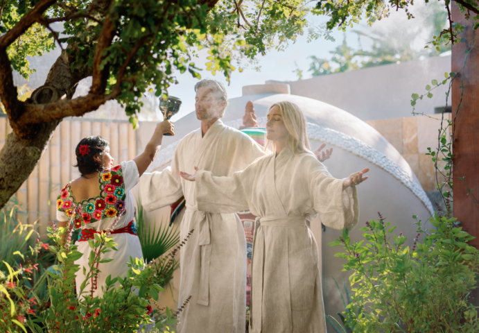 a group of people in white robes standing under a tree