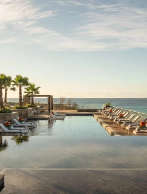 a pool with lounge chairs and a large body of water