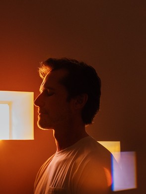 a man standing in front of a window with light coming out of the window