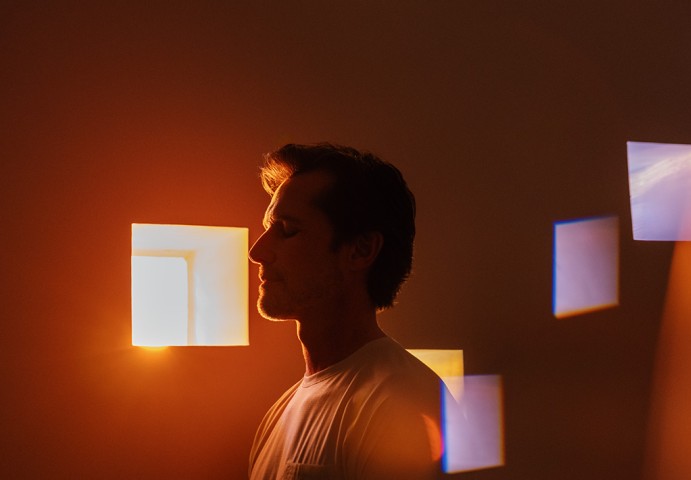 a man standing in front of a window with light coming out of the window