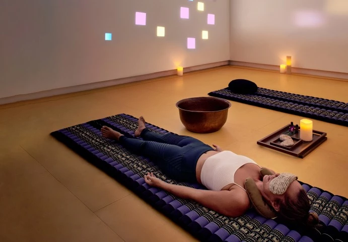 a woman lying on a mat with a mask on her face