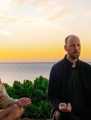 two men meditating on a beach