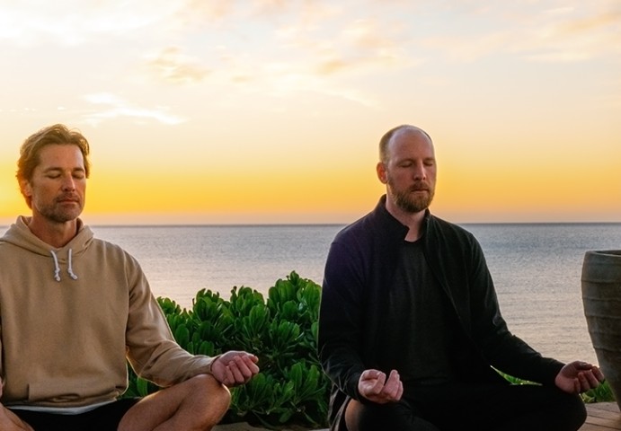 two men meditating on a beach