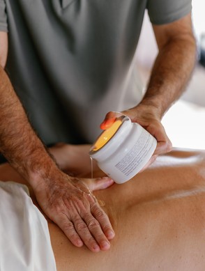 a man pouring a cream onto a person's back