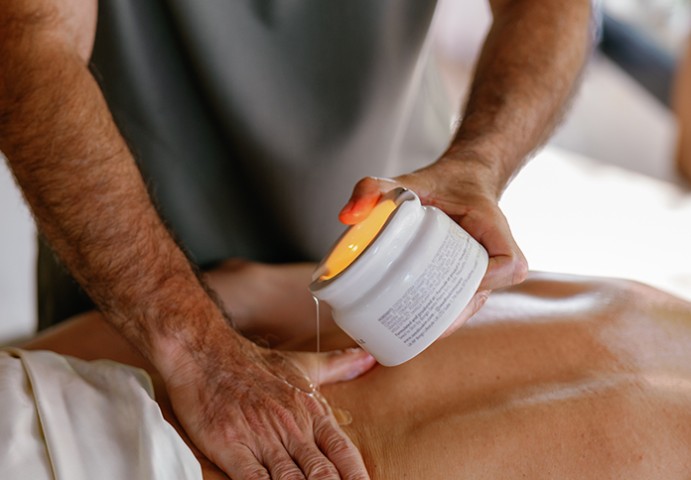 a man pouring a cream onto a person's back