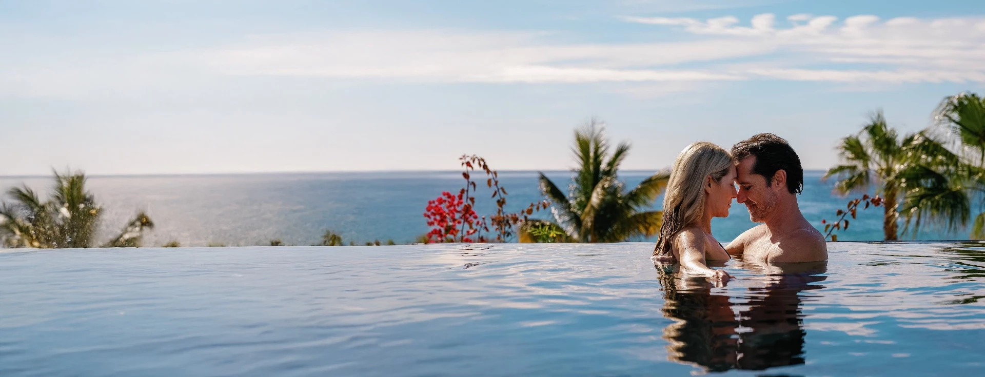 a woman in a pool with a body of water and palm trees