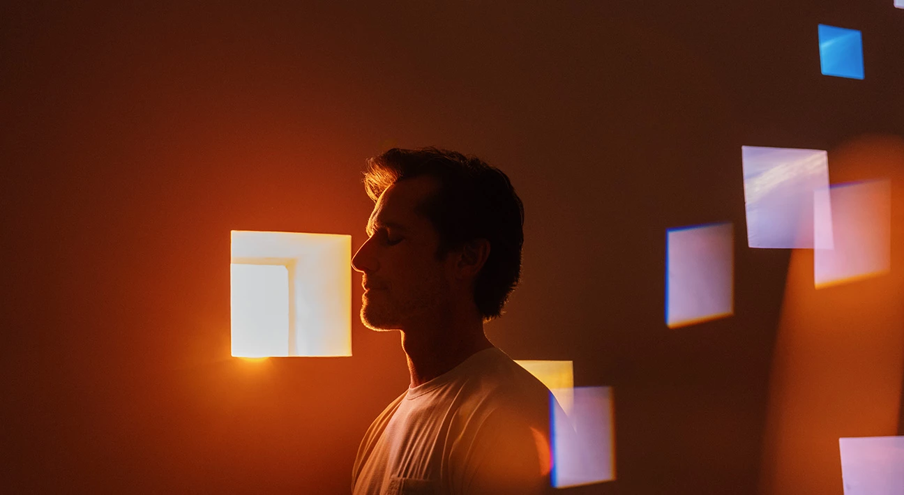 a man standing in front of a window with light coming out of the window