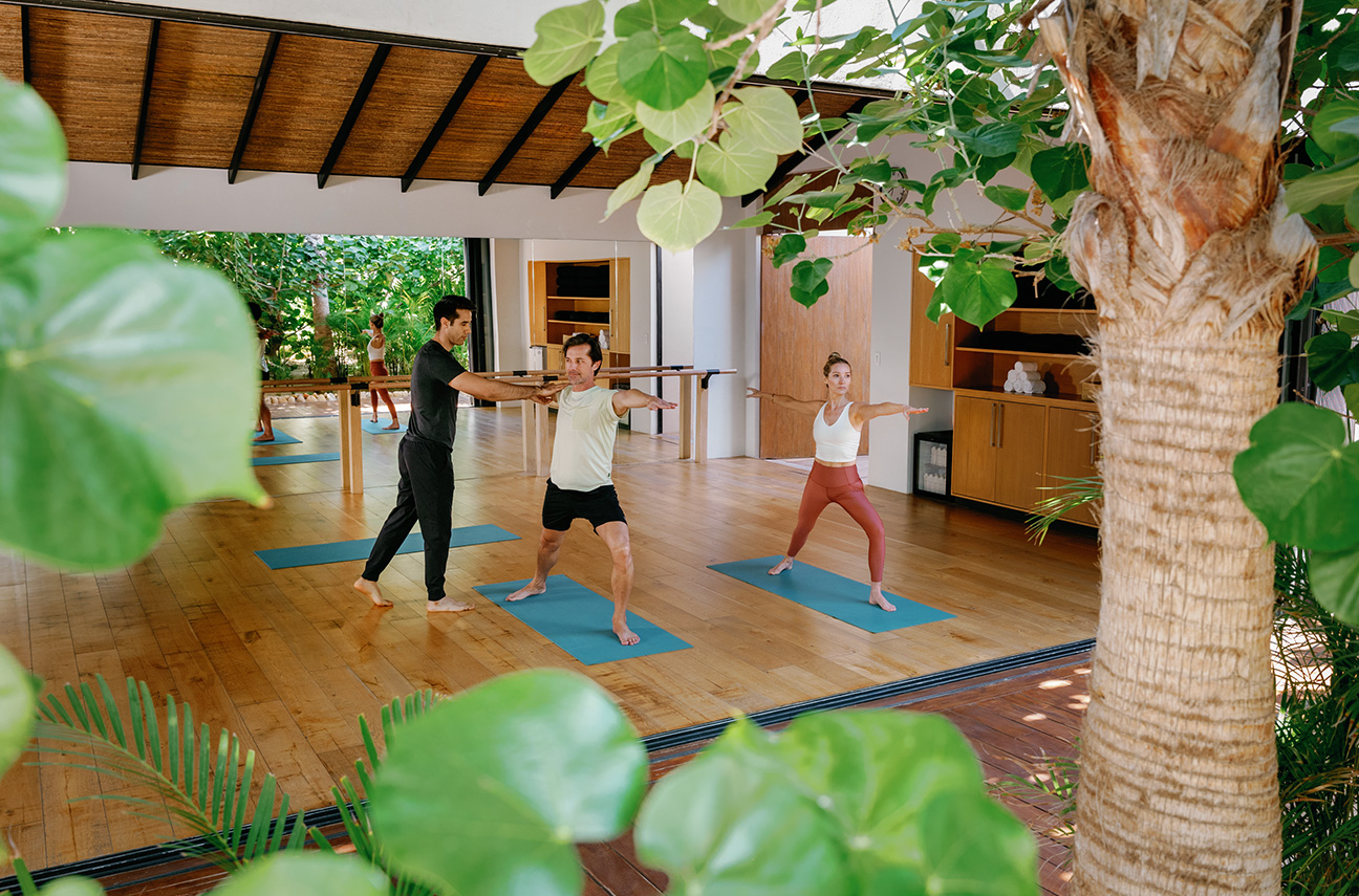 a group of people doing yoga in a room with trees