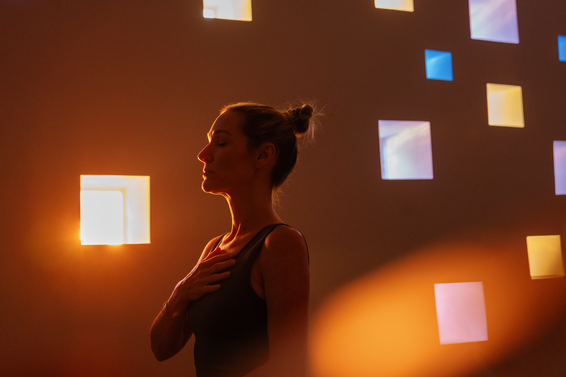 a woman standing in front of a wall with square windows